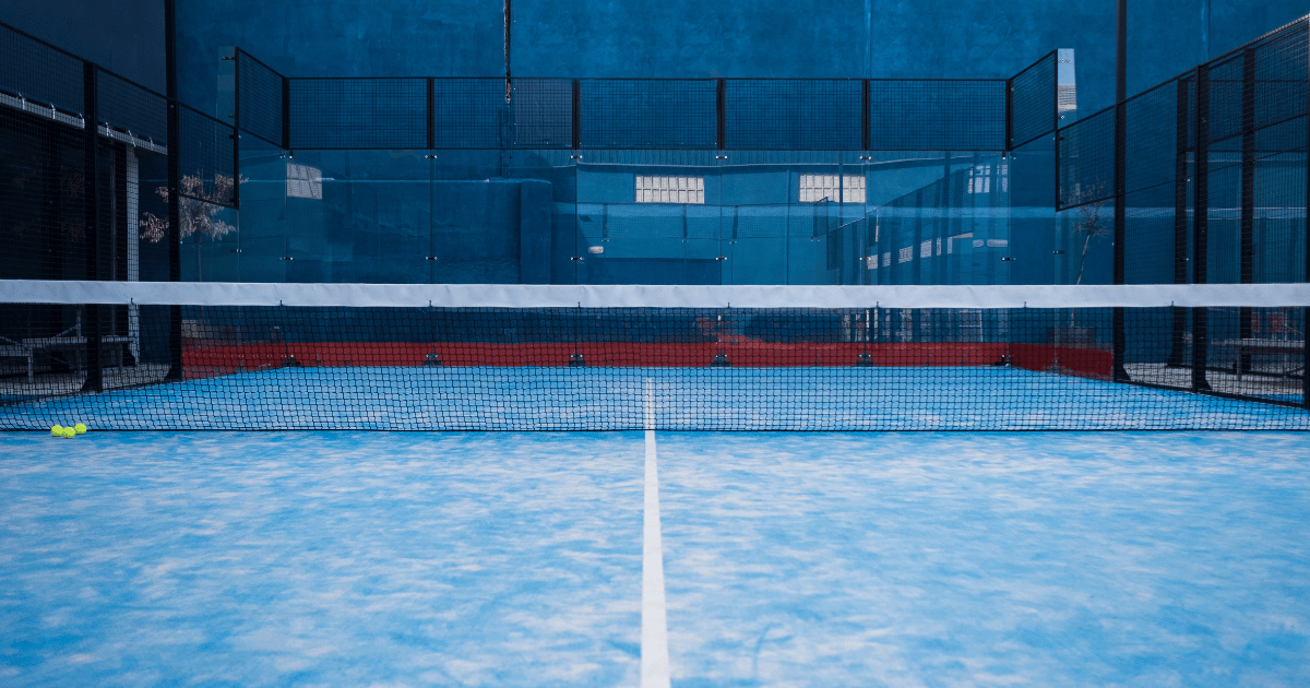 Indendørs padelbane med net og glasvægge